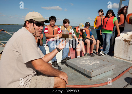 Il biologo marino mostra campione di acqua per gli studenti delle scuole medie a bordo di navi di ricerca durante il campo classe di viaggio nel Golfo del Messico Foto Stock