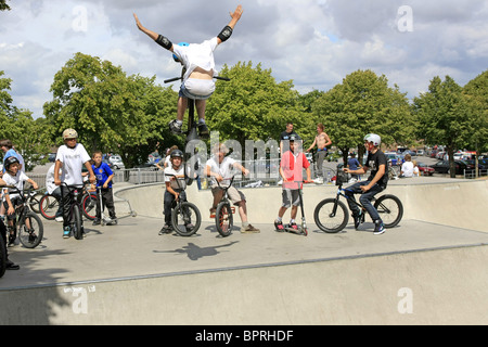 Un gruppo di ragazzi adolescenti guardare un amico maschio eseguire alcuni trucchi su una bmx bike a uno skateboard park Foto Stock