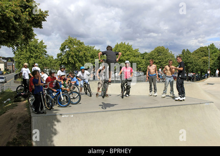 Un gruppo di ragazzi adolescenti guardare un amico maschio eseguire alcuni trucchi su una bmx bike a uno skateboard park Foto Stock