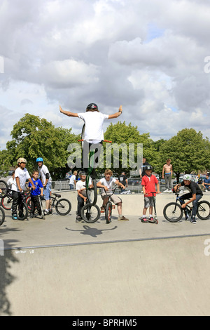 Un gruppo di ragazzi adolescenti guardare un amico maschio eseguire alcuni trucchi su una bmx bike a uno skateboard park Foto Stock