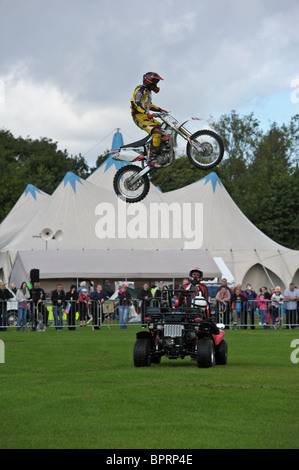 Motociclo stuntman vola in aria sopra la testa di un altro stunt man come la folla guarda lui a una mostra di estate Foto Stock