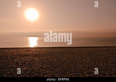 Tramonto sul mare e una spiaggia ghiaiosa Foto Stock