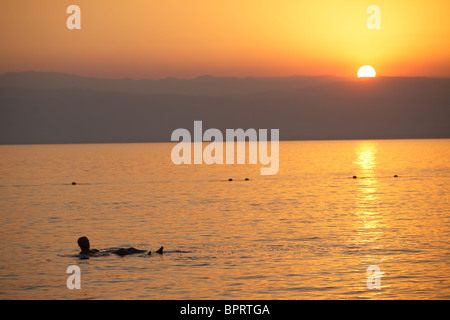 L'uomo fluttuante nel mar morto al tramonto, Giordania Foto Stock