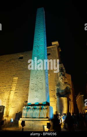 Night Shot di statue illuminato e obelisco di Ramesse II. nella parte anteriore del primo pilone del Tempio di Luxor, Tebe, Egitto, Arabia Foto Stock