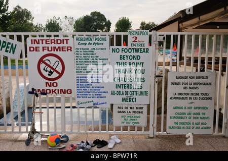 Moltitudine di bilingue segnaletica di avvertimento e le regole all'entrata di una piscina in Francia Foto Stock