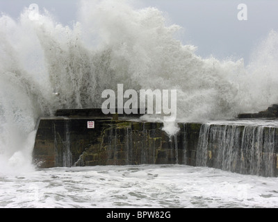 Un enorme ondata rottura oltre la parete del mare a Lamorna Cove, Cornwall, Regno Unito Foto Stock