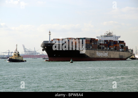 La Bangkok Express con i rimorchiatori presenze in partenza Porto di Southampton England Regno Unito Foto Stock