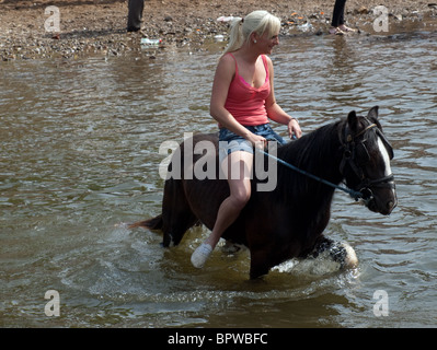 Giovane donna in pantaloncini corti e strappy tee-shirt equitazione bareback presso il famoso viaggiatori annuale raduno a Appleby Horse Fair, Cumbria Inghilterra England Regno Unito Foto Stock