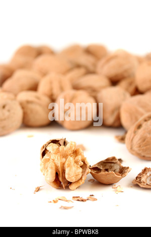 Tutta le noci in una pila con uno rotto nella parte anteriore che mostra il dado su sfondo bianco Foto Stock