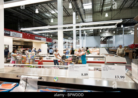 Shoppers vagare navate della sezione alimentare della Costco USA con grande shopping carts stipati con cibo e beni durevoli venduti alla rinfusa Foto Stock