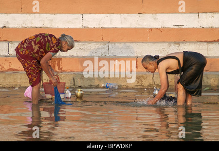 Donne che svolgono servizio lavanderia a Ghat lungo il fiume Gange a Varanasi India Foto Stock