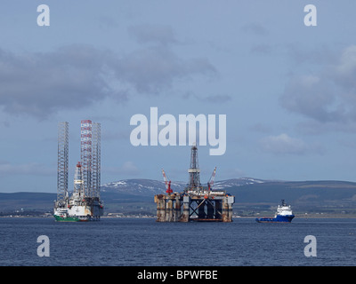 Le ancore di un semi-sommergibile oil rig sono sollevati da due anchor handling navi in Cromarty Firth, nei pressi di una galassia di sollevare con un martinetto Foto Stock