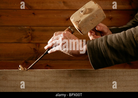 Scanalare scalpello di legno falegname attrezzo martello in mano lavorando sullo sfondo di legno Foto Stock