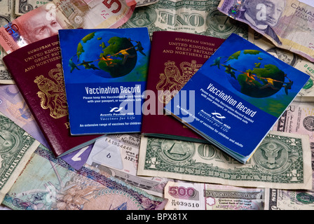 Regno Unito i passaporti e i libri di vaccinazione posa su varie banconote provenienti da tutto il mondo, compresi i dollari americani. Foto Stock