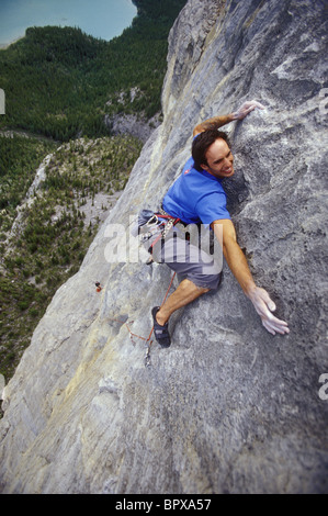 Alta su una scogliera, un maschio di rocciatore ricerche per il suo prossimo tenere in mano Foto Stock