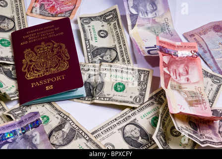 Regno Unito passaporti posa su varie banconote provenienti da tutto il mondo, compresi i dollari americani, dollari canadesi. Foto Stock