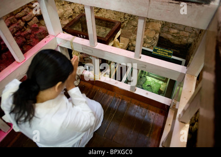 Donna buddista pregando oltre la pietra originale di riferimento nel luogo di nascita di Buddha, Lumbini, Nepal. Foto Stock