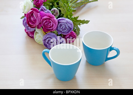 Fiori e vuoto di due tazze di caffè sul tavolo Foto Stock