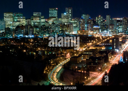 Calgary, Alberta, Canada skyline notturno con un loop di strada con la testa e le luci di coda in primo piano. Foto Stock