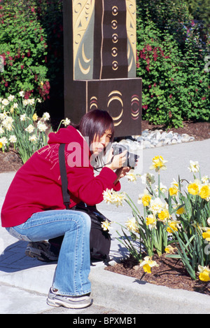 Donna prendendo foto di fiori con fotocamera digitale, Vancouver, BC, British Columbia, Canada - Asian Tourist Foto Stock