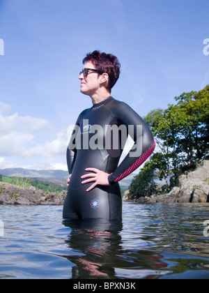 Una donna in Coniston Water in procinto di prendere parte alla sempre più diffusa di attività all'aperto o Wild nuoto. Foto Stock