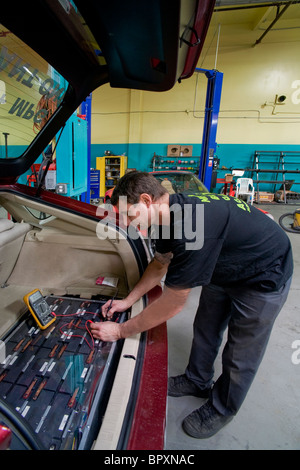 Un tecnico in un veicolo California modifica shop controlla la tensione di una Toyota Prius ibrida auto della guida principale batteria Foto Stock