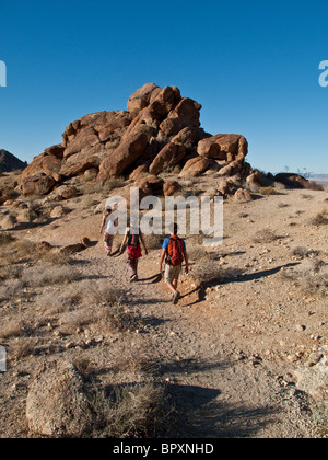 Tre escursionisti negoziare la rocky oasi di Mara area nel Parco nazionale di Joshua Tree Foto Stock