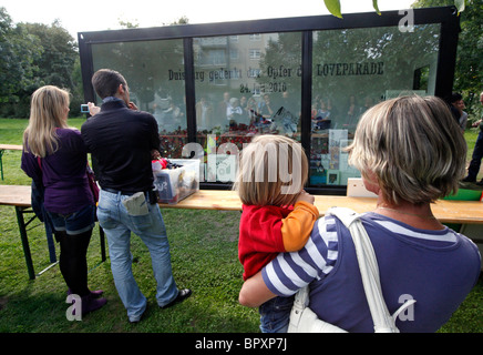 Duisburg Loveparade 2010: cubo di vetro presso il sito della tragedia in cui il dolore dei regali, candele e giocattoli sono mantenuti da ricordare Foto Stock