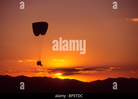 Un parapendio in tandem pilota e passeggero salire oltre il Jackson Hole, Wyoming al tramonto. Foto Stock