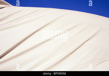 Dettaglio del telone bianco ben teso su grandi leggermente ricurva oggetto creando increspature sotto il cielo blu Foto Stock