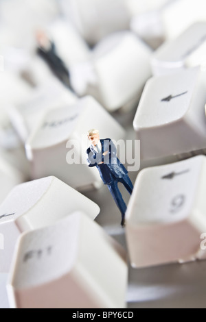 Business figurine collocato con tasti dalla tastiera di un computer Foto Stock