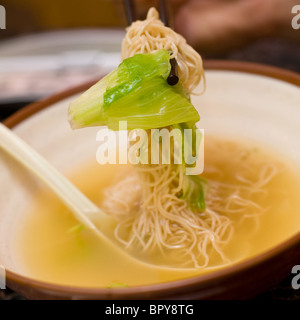 Close up di gamberetti zuppa wonton mangiata con il cucchiaio e bacchette al ristorante cinese Foto Stock
