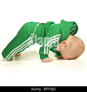 Carino espressivo baby boy isolati su sfondo bianco cercando di stand per la prima volta. Foto Stock