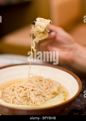 Gamberetti zuppa wonton mangiata con il cucchiaio e bacchette al ristorante cinese Foto Stock