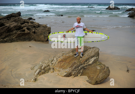 Un surfista, Ben Howey, tenendo un longboard tavole da surf sulla spiaggia di Fistral, Newquay, Regno Unito del surf di capitale, in Cornovaglia Foto Stock