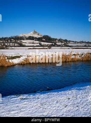 Glastonbury Tor si affaccia sul fiume Brue a South Moor nella neve invernale. Glastonbury, Somerset, Inghilterra. Foto Stock