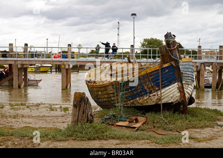 Abbandonata e abbandonato la pesca in barca sulle velme del porto di segale in East Sussex con nuova imbarcazione di salvataggio Jetty in background Foto Stock