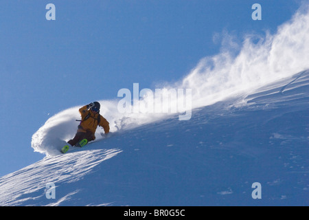 Un uomo sci polvere di neve in una giornata ventosa sul vertice Donner in California. Foto Stock