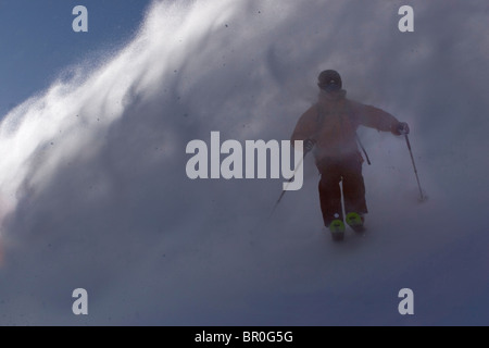 Un uomo sci polvere di neve in una giornata ventosa sul vertice Donner in California. Foto Stock