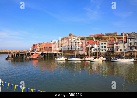 RNLI scialuppa di salvataggio e barche nel porto di inferiore sotto la chiesa di Saint Mary, Whitby, North Yorkshire, Inghilterra, Regno Unito. Foto Stock