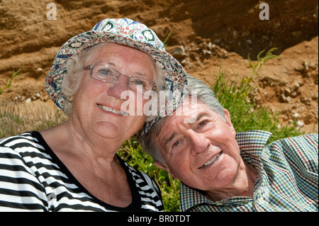 Coppia di anziani seduti su una giornata d'estate sorridente. Foto Stock