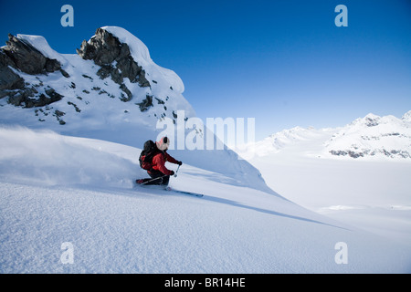 Uomo di telemark sci giù per la collina in Alaska backcountry vicino i confini del Canada Foto Stock