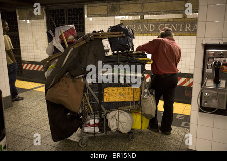 Senzatetto uomo con i suoi beni sulla piattaforma della metropolitana nella Grand Central 42nd Street Station in New York City Foto Stock