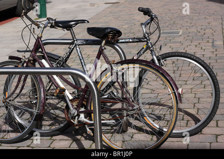 2 vecchie biciclette appoggiata contro una bicicletta riposo in Station Road, New Milton Foto Stock