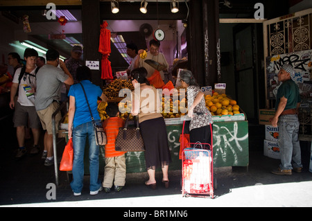 Gli acquirenti di acquistare la frutta a un cavalletto di frutta sulla Mott Street a Chinatown in New York Foto Stock