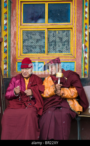 Monaci buddisti tibetani chat durante la filatura ruote della preghiera e diteggiatura perle, Tagong Monastero, nella provincia di Sichuan, in Cina Foto Stock