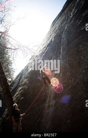 Un uomo si arrampica come un altro belays in Yosemite, CA. Foto Stock