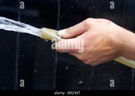 Tubo flessibile con acqua proveniente dalla tenuta in un uomo di sinistra. Foto Stock