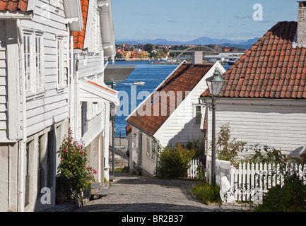 Gamle Stavanger, parte della vecchia città di Stavanger, bianco imbarcati case, power boat nel lontano porto Foto Stock