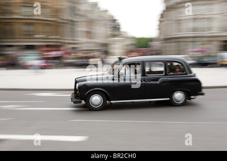 Londra taxi accelerando attraverso Trafalgar Square Foto Stock